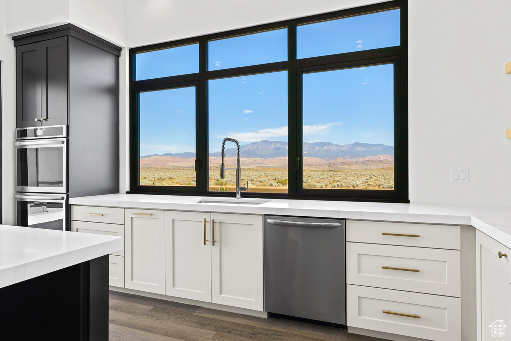 Kitchen featuring stainless steel appliances, dark wood-type flooring, a mountain view, and white cabinetry