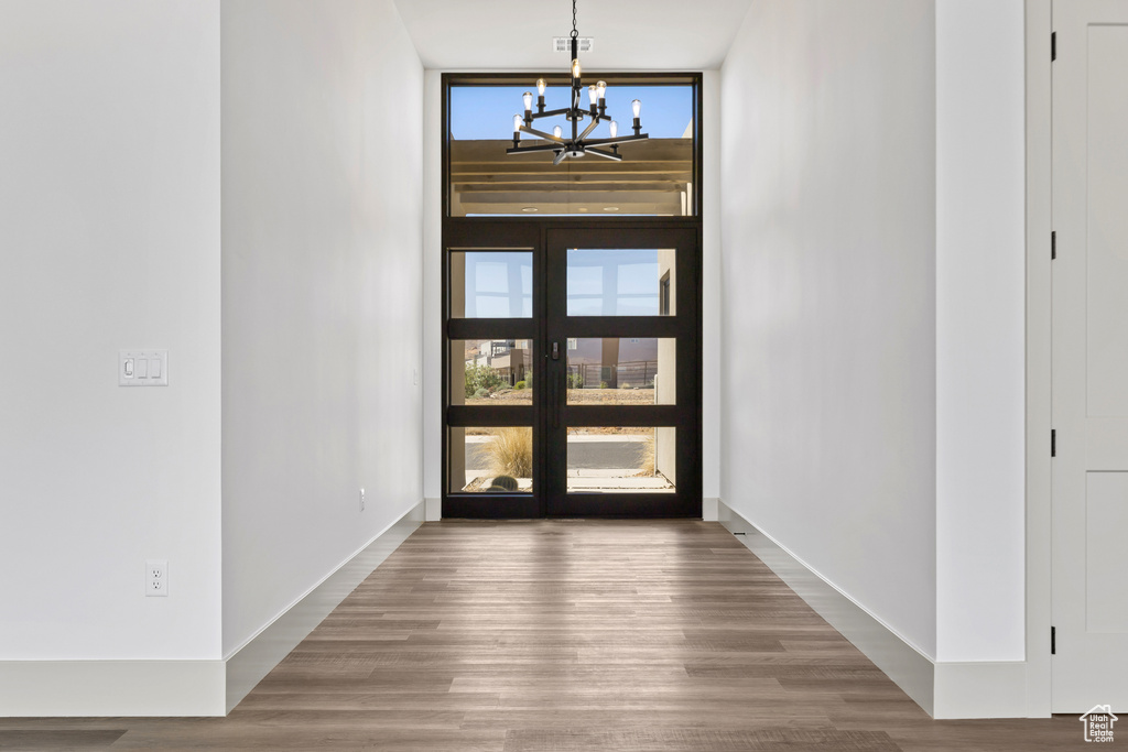 Foyer featuring a chandelier, wood finished floors, plenty of natural light, and a wall of windows
