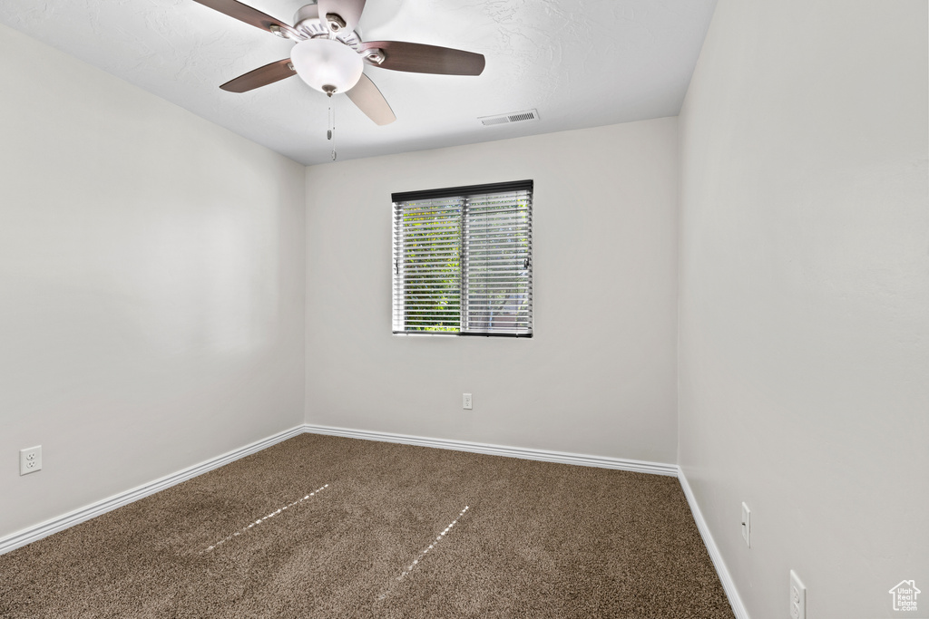 Carpeted empty room with baseboards and ceiling fan
