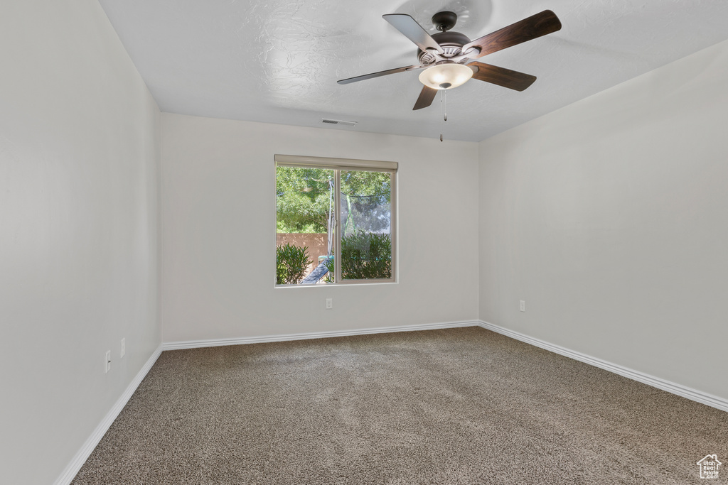 Carpeted spare room with ceiling fan and baseboards
