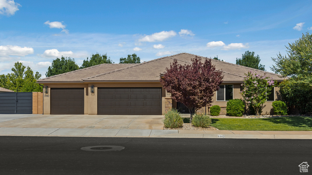 View of front of house featuring concrete driveway, an attached garage, stucco siding, and a tiled roof