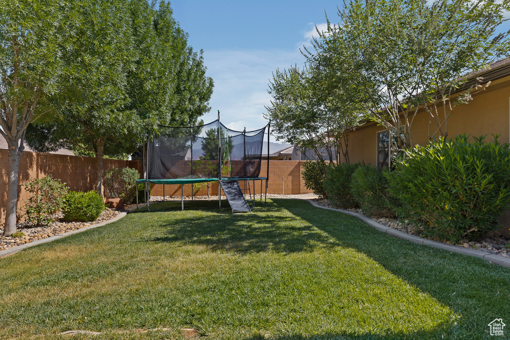 Fenced backyard featuring a trampoline