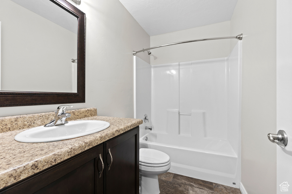 Bathroom featuring vanity, shower / bath combination, and stone finish flooring