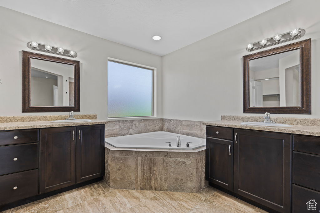 Bathroom featuring two vanities and a garden tub
