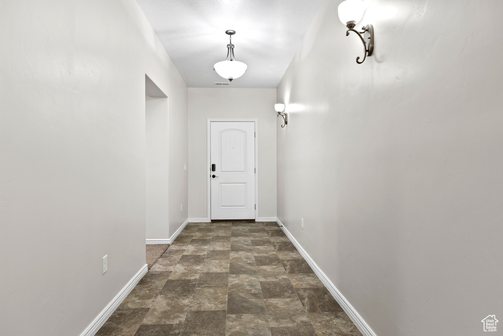 Doorway to outside with stone finish floors and baseboards