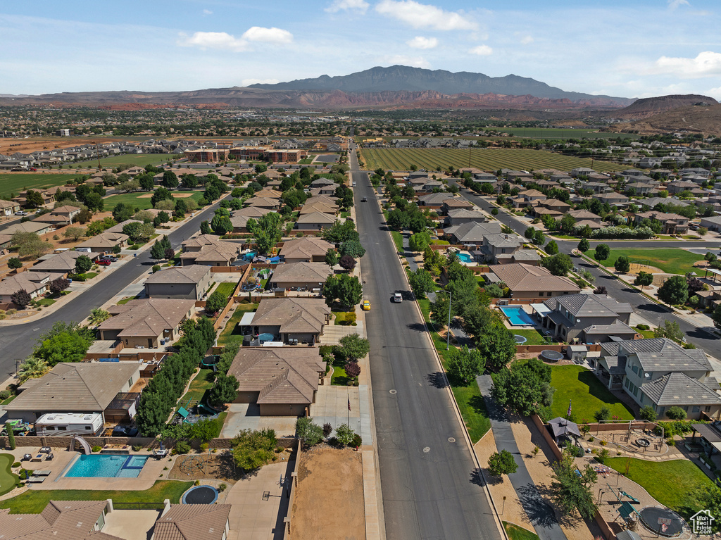 Aerial view of property and surrounding area featuring mountains and nearby suburban area