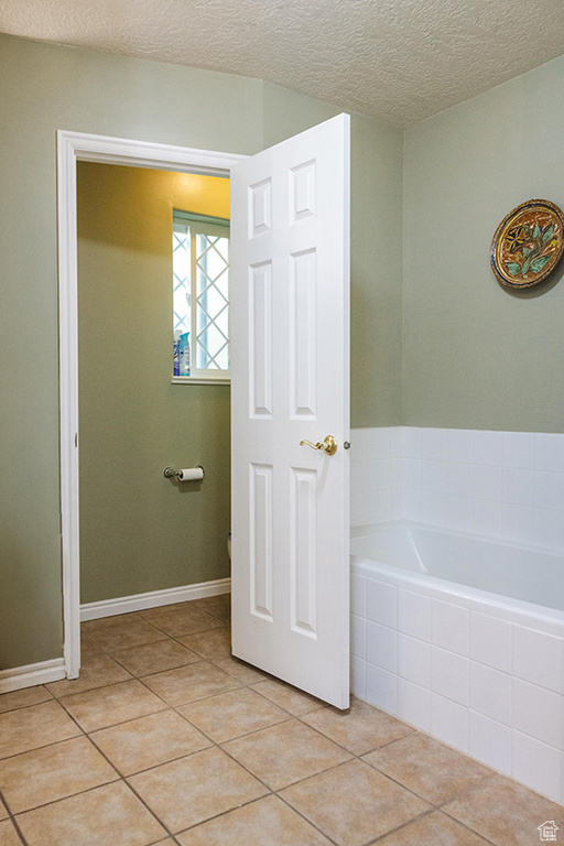 Bathroom featuring a garden tub, tile patterned flooring, and a textured ceiling