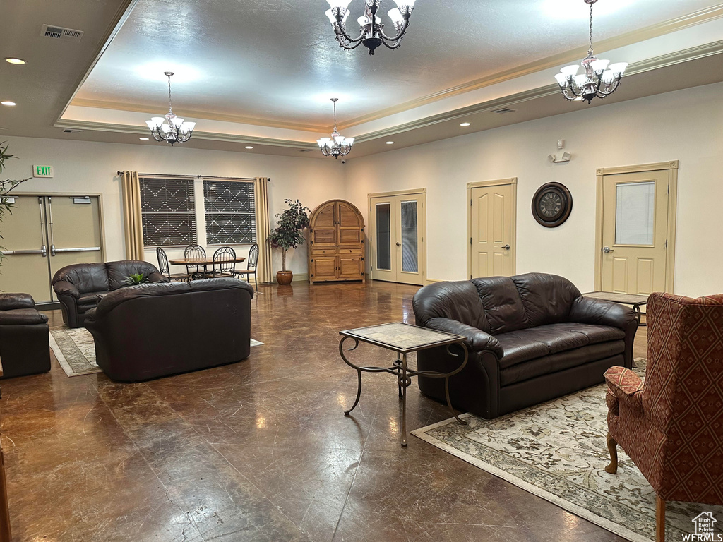 Living room featuring a chandelier, a raised ceiling, recessed lighting, and crown molding