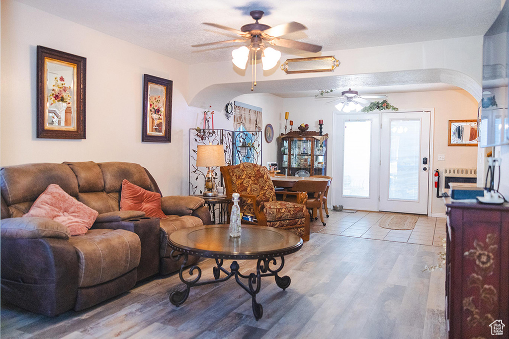 Living area featuring a ceiling fan, wood finished floors, and arched walkways