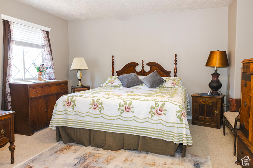 Bedroom featuring light carpet and a textured ceiling