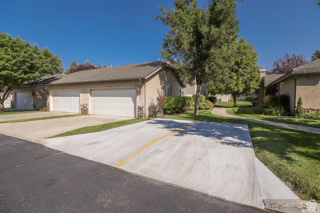View of front of property featuring a front yard, concrete driveway, and a garage