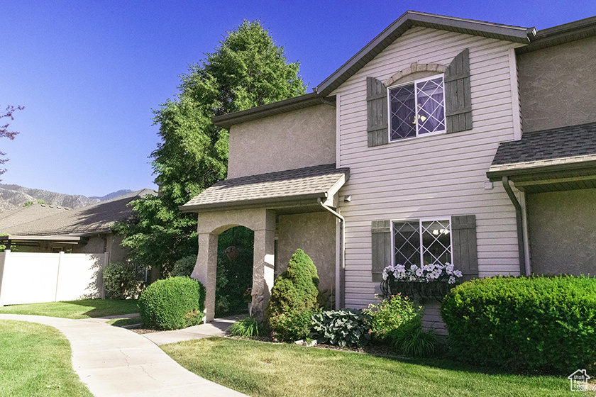 View of front of home with stucco siding and a shingled roof