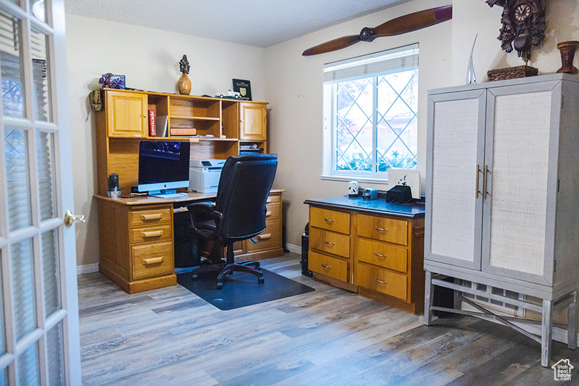 Home office with light wood-style floors and ceiling fan