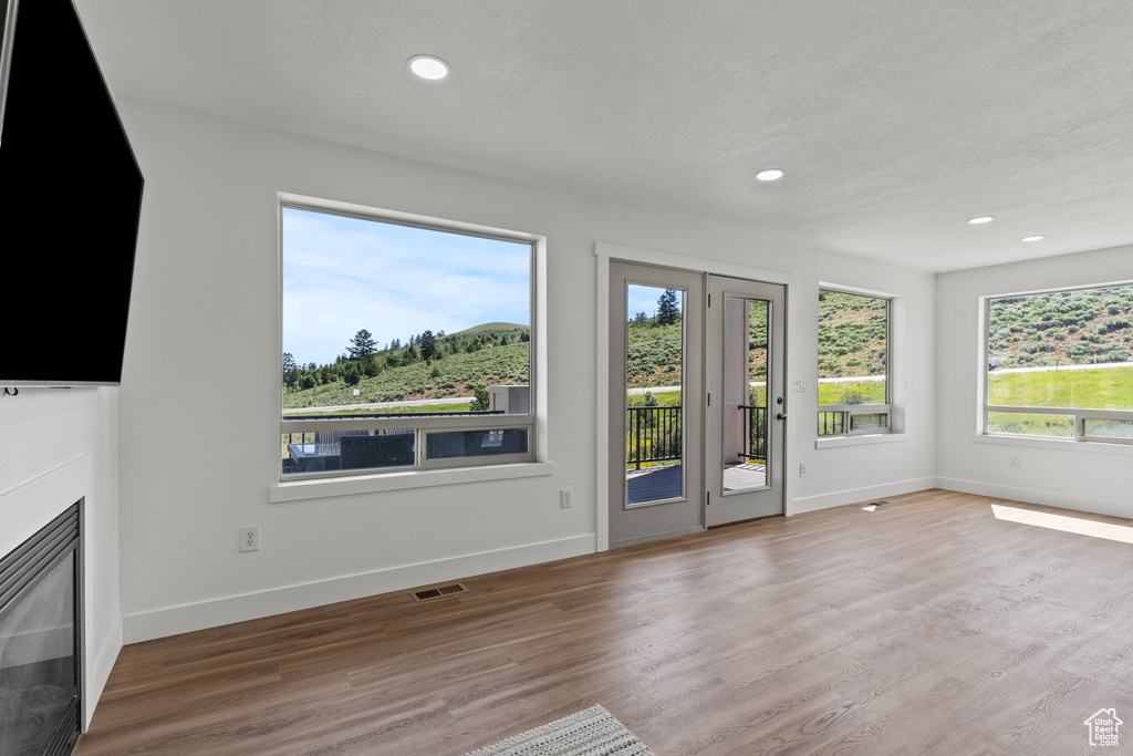 Unfurnished living room featuring recessed lighting, wood finished floors, and a glass covered fireplace