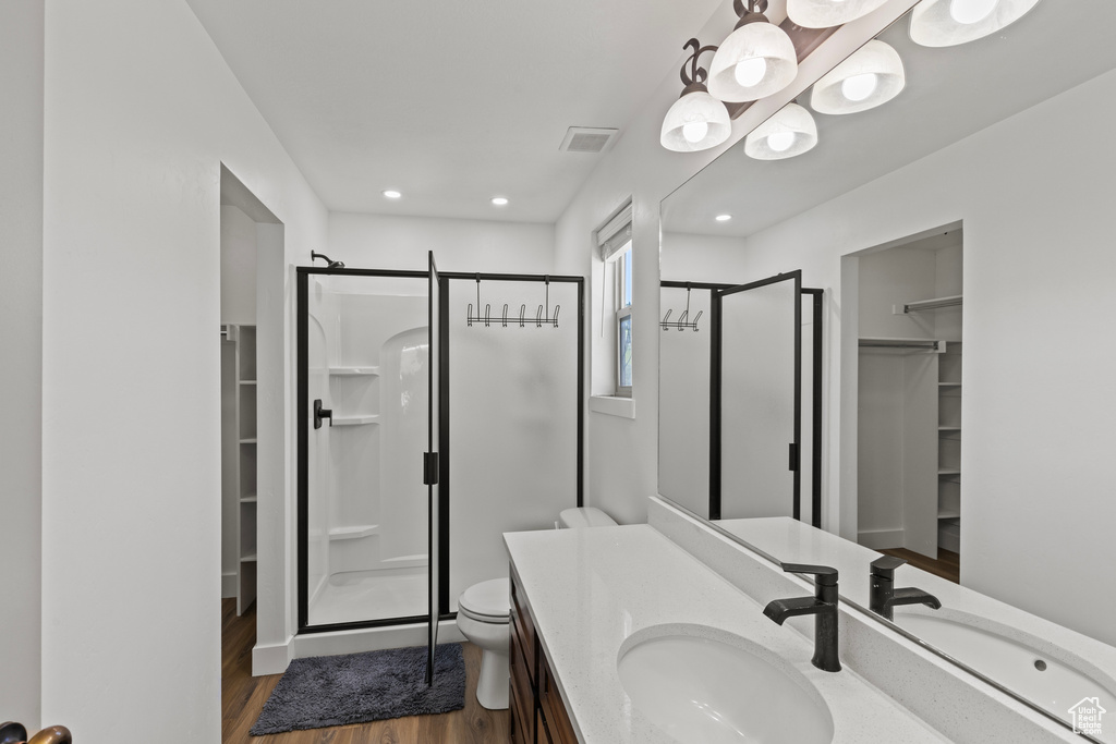 Full bath featuring a spacious closet, a stall shower, vanity, wood finished floors, and recessed lighting