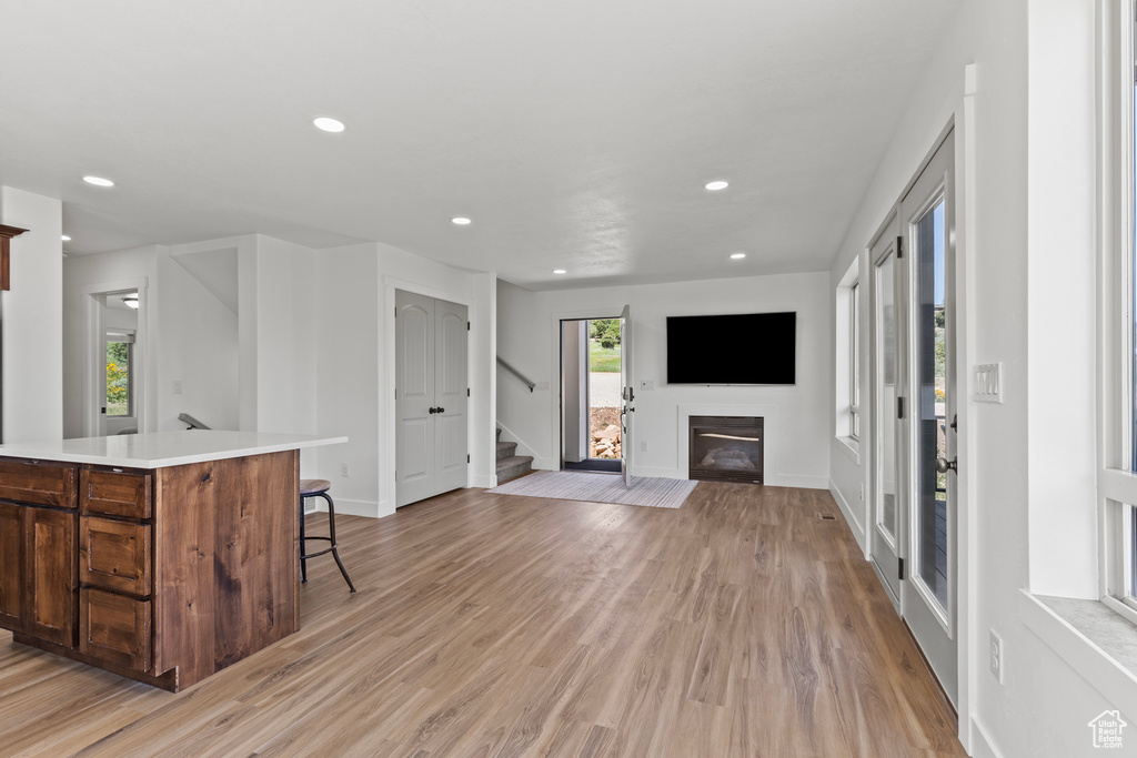Kitchen with a kitchen breakfast bar, a glass covered fireplace, recessed lighting, light countertops, and light wood finished floors