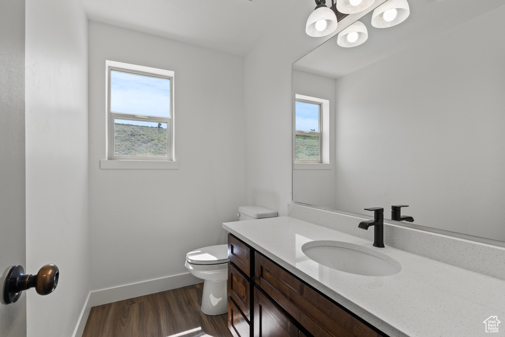 Half bathroom with wood finished floors, vanity, and a chandelier