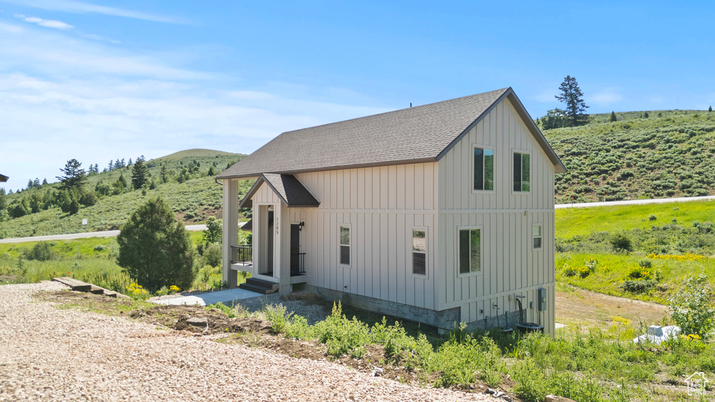 View of side of home with a shingled roof, board and batten siding, and a mountain view