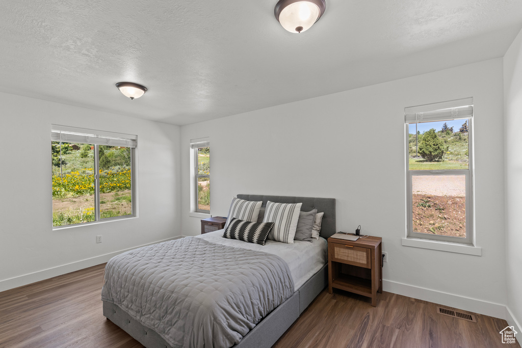 Bedroom with wood finished floors and a textured ceiling