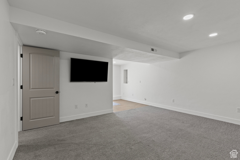 Carpeted empty room featuring a smoke detector and recessed lighting