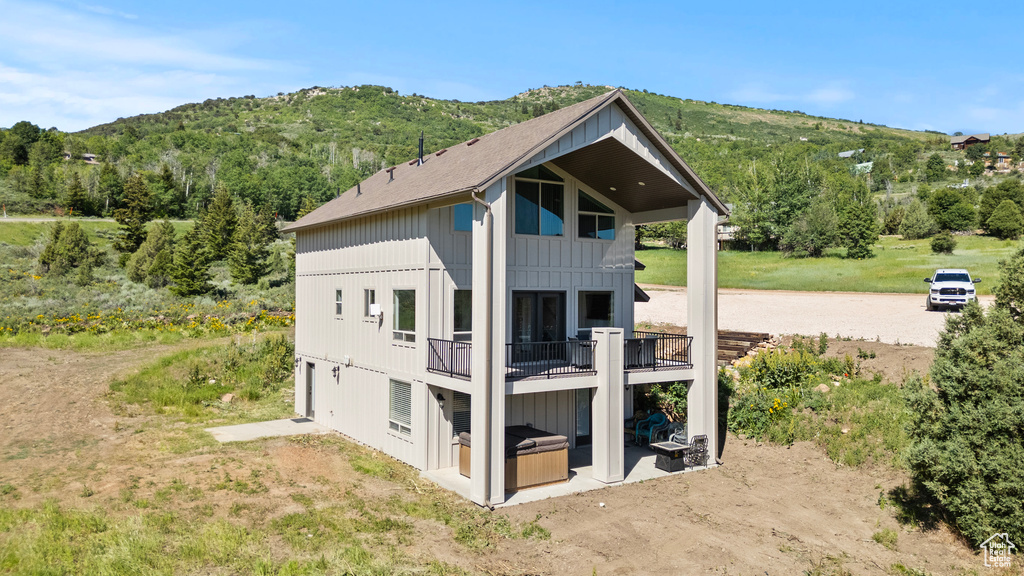 Back of house featuring board and batten siding, a shingled roof, and a mountain view