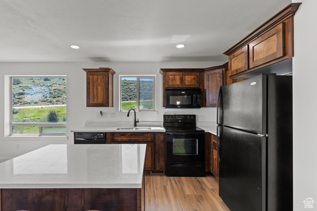 Kitchen with black appliances, light countertops, plenty of natural light, light wood-style flooring, and recessed lighting