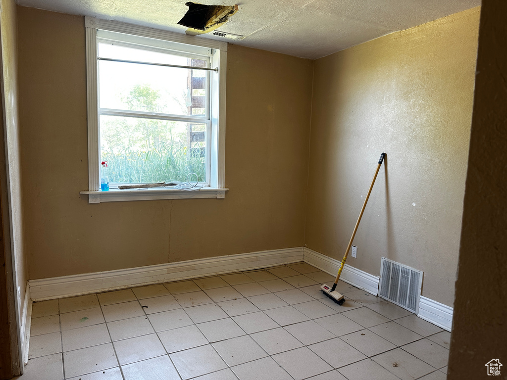 Empty room with a textured ceiling and light tile patterned floors