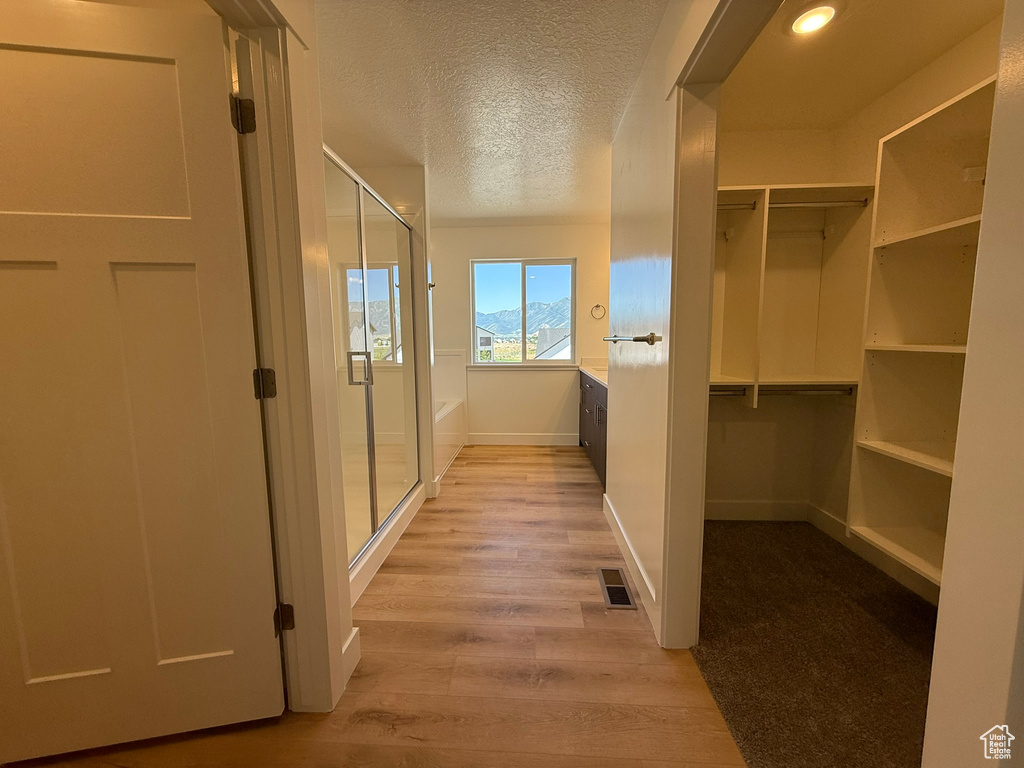 Corridor featuring light wood-style floors and a textured ceiling