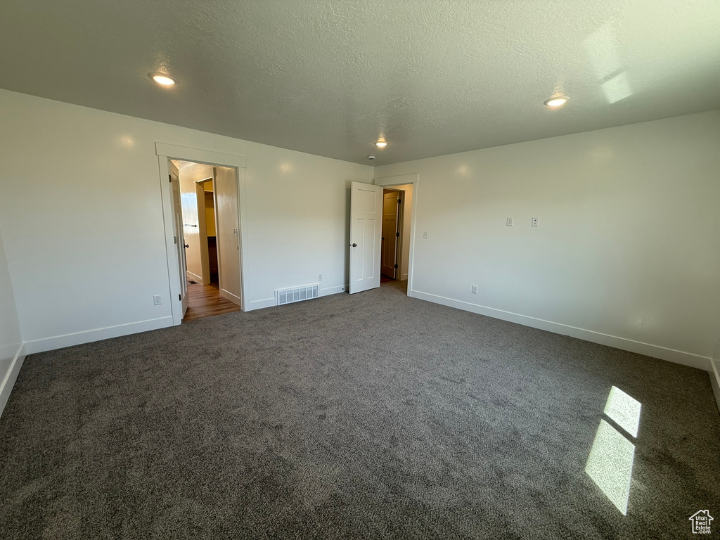 Unfurnished bedroom with dark colored carpet, a textured ceiling, and recessed lighting