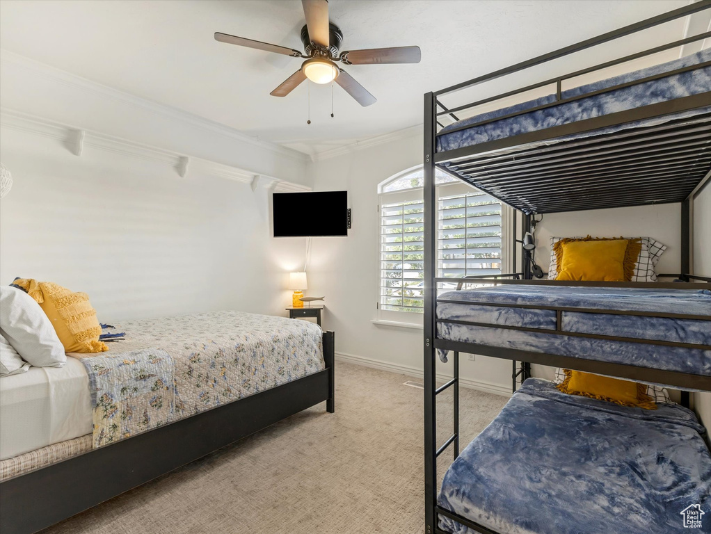 Bedroom with carpet, ornamental molding, and a ceiling fan