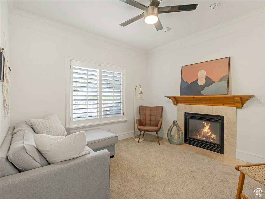 Living room featuring crown molding, a tiled fireplace, and a ceiling fan