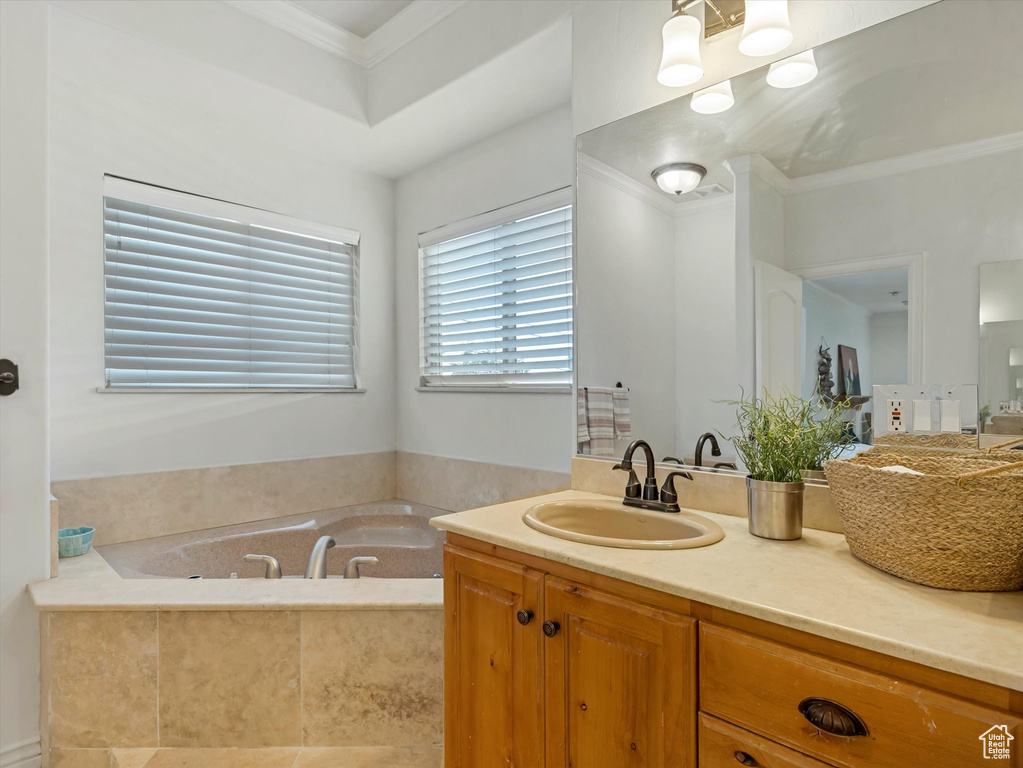 Bathroom featuring ornamental molding, a garden tub, and vanity