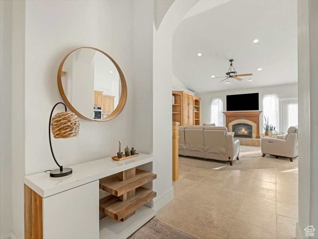 Corridor featuring arched walkways, recessed lighting, light tile patterned floors, and lofted ceiling