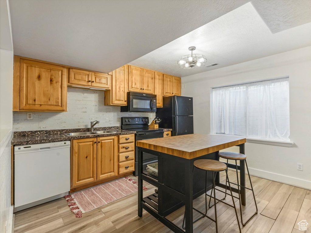 Kitchen featuring black appliances, light wood-type flooring, a chandelier, and butcher block countertops
