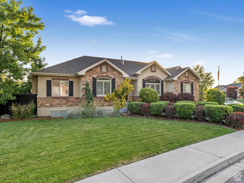 Ranch-style home with stone siding, stucco siding, and a shingled roof