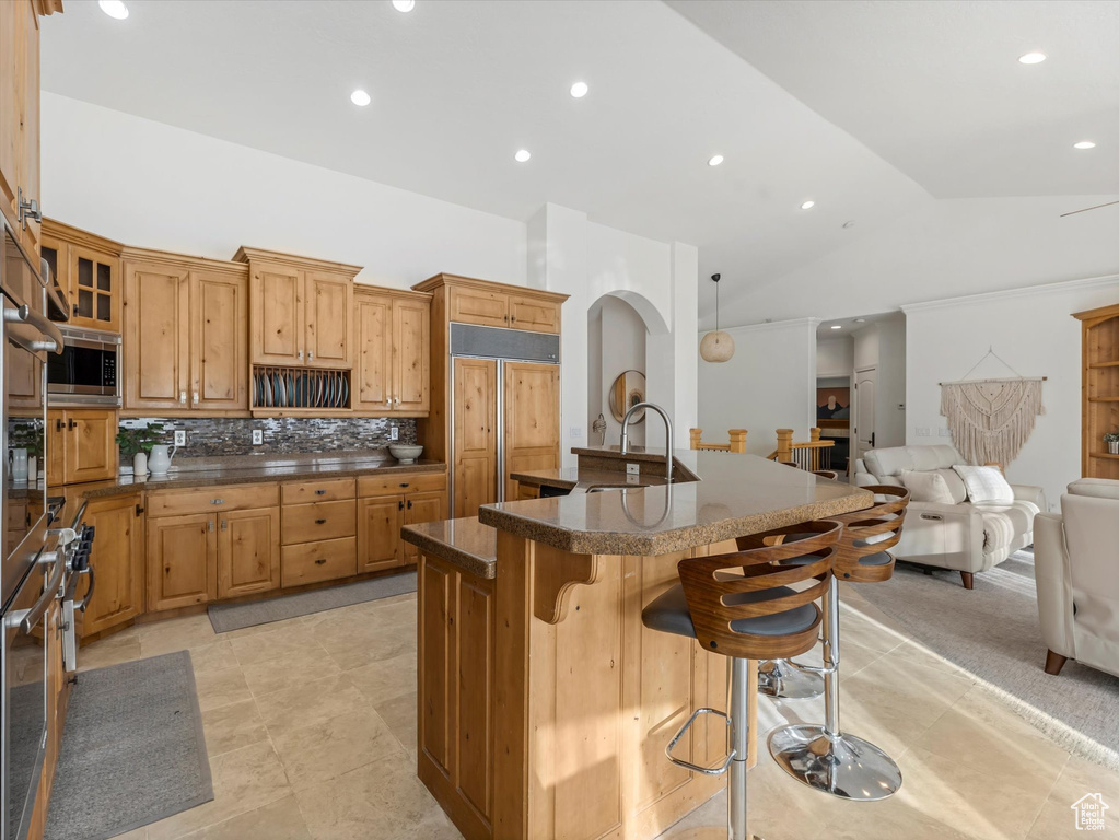 Kitchen featuring paneled fridge, stainless steel microwave, a kitchen breakfast bar, open floor plan, and lofted ceiling