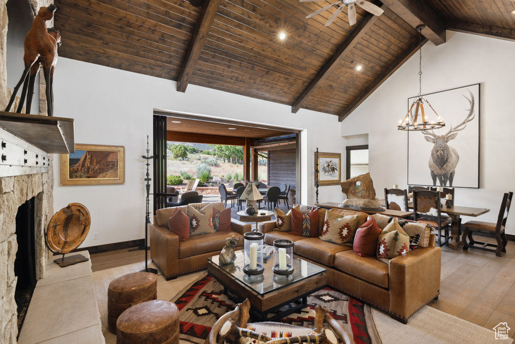 Living room with hardwood / wood-style flooring, a wood ceiling with exposed beams, a stone fireplace, high vaulted ceiling, and a ceiling fan