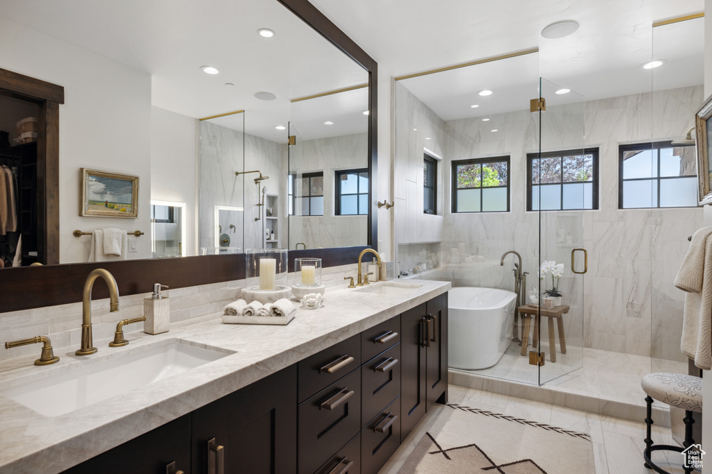 Bathroom featuring a marble finish shower, a freestanding tub, double vanity, tile walls, and recessed lighting