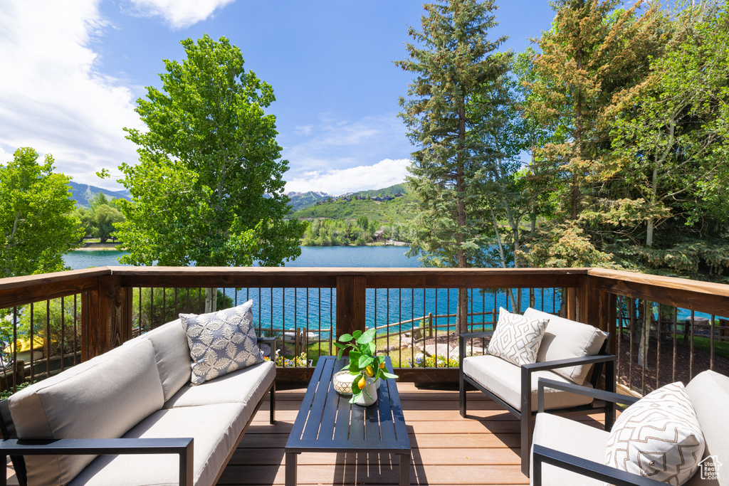 Deck with an outdoor living space and a water and mountain view