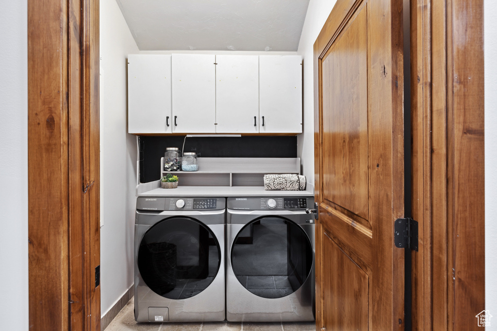 Washroom featuring cabinet space and independent washer and dryer