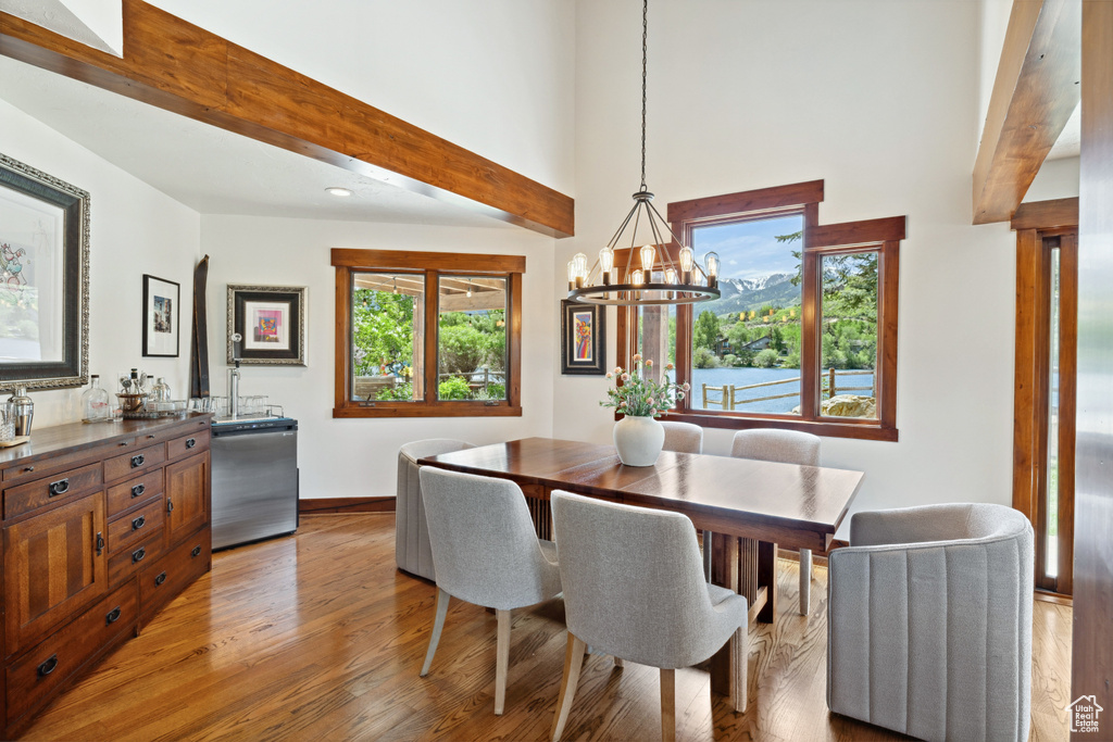 Dining room featuring light wood-style floors, healthy amount of natural light, a chandelier, recessed lighting, and beam ceiling