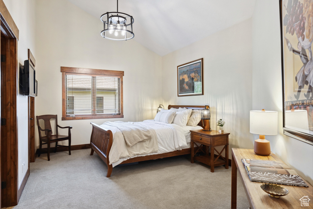 Bedroom featuring light colored carpet, a chandelier, and high vaulted ceiling