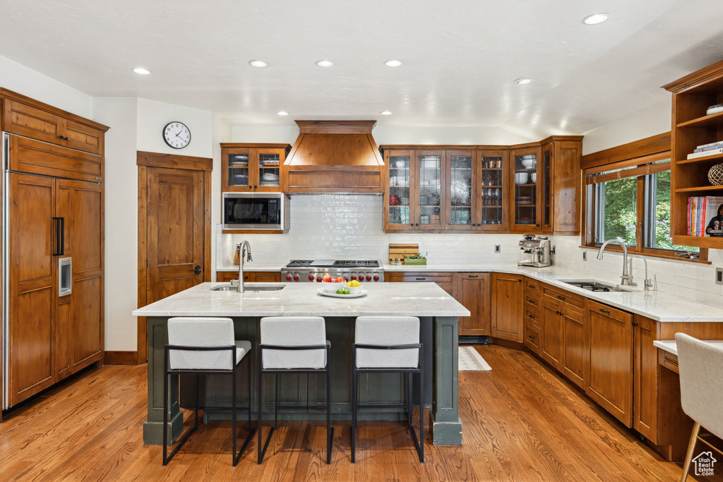 Kitchen featuring built in appliances, custom range hood, open shelves, light wood-type flooring, and recessed lighting