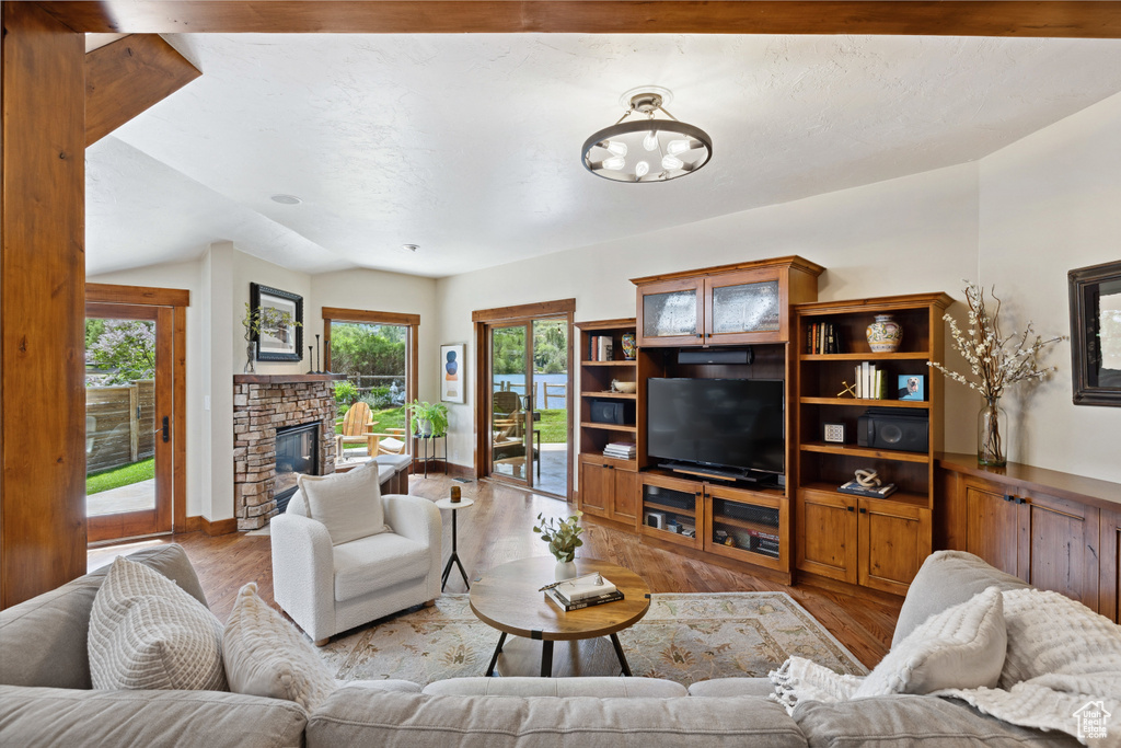 Living area with light wood finished floors, a chandelier, a fireplace, and vaulted ceiling