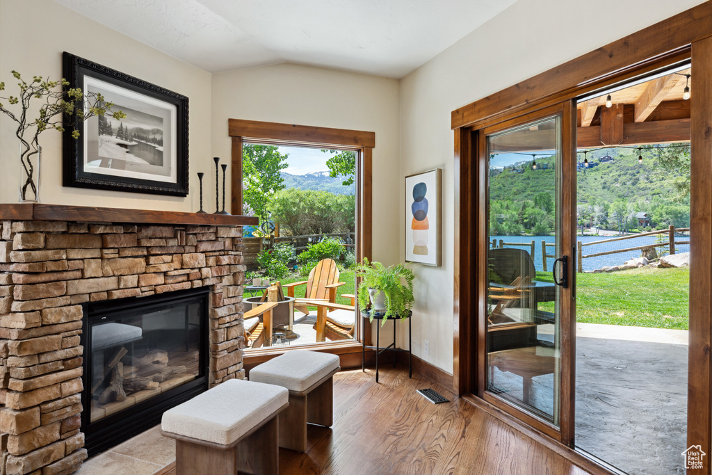 Sitting room featuring wood finished floors, lofted ceiling, a stone fireplace, and a mountain view