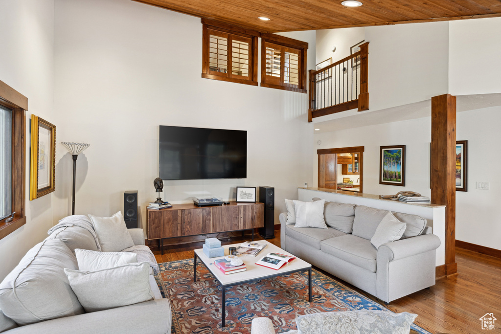 Living room with a high ceiling, recessed lighting, wood finished floors, and wooden ceiling