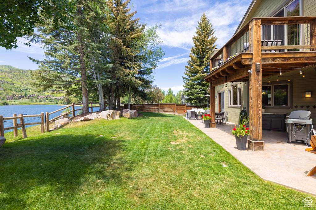 Fenced backyard featuring a water view and a patio