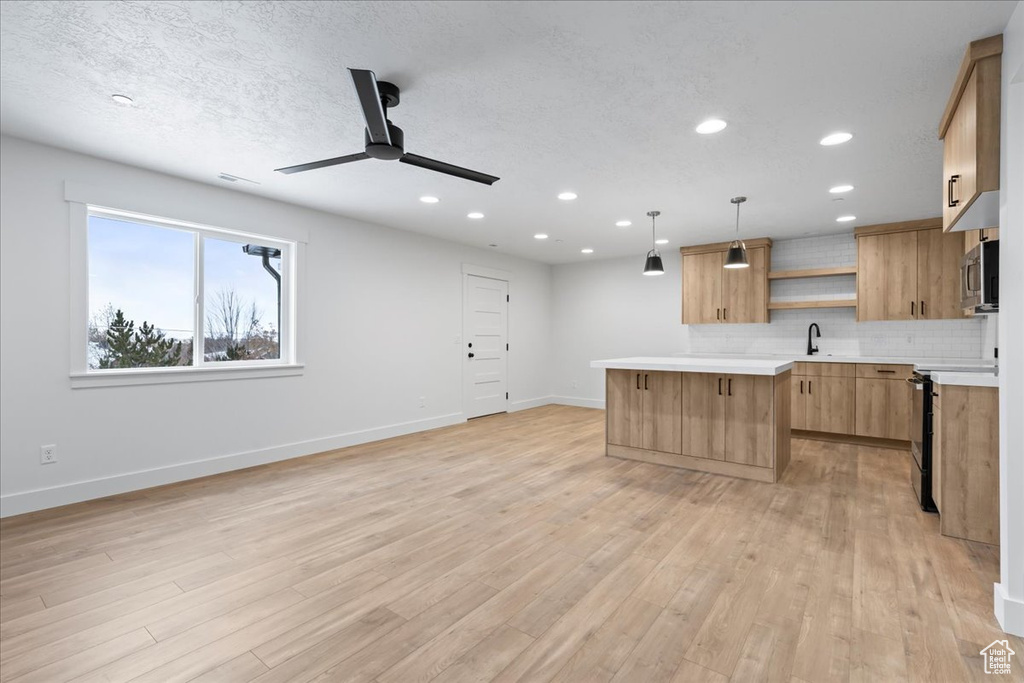 Kitchen with open shelves, stainless steel microwave, a ceiling fan, tasteful backsplash, and light countertops