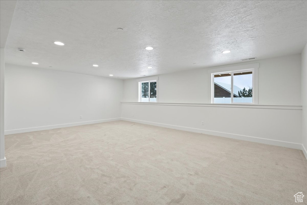 Below grade area featuring recessed lighting, a textured ceiling, and carpet floors