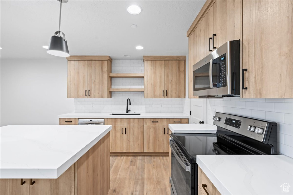 Kitchen with appliances with stainless steel finishes, light brown cabinets, open shelves, tasteful backsplash, and light wood-style flooring